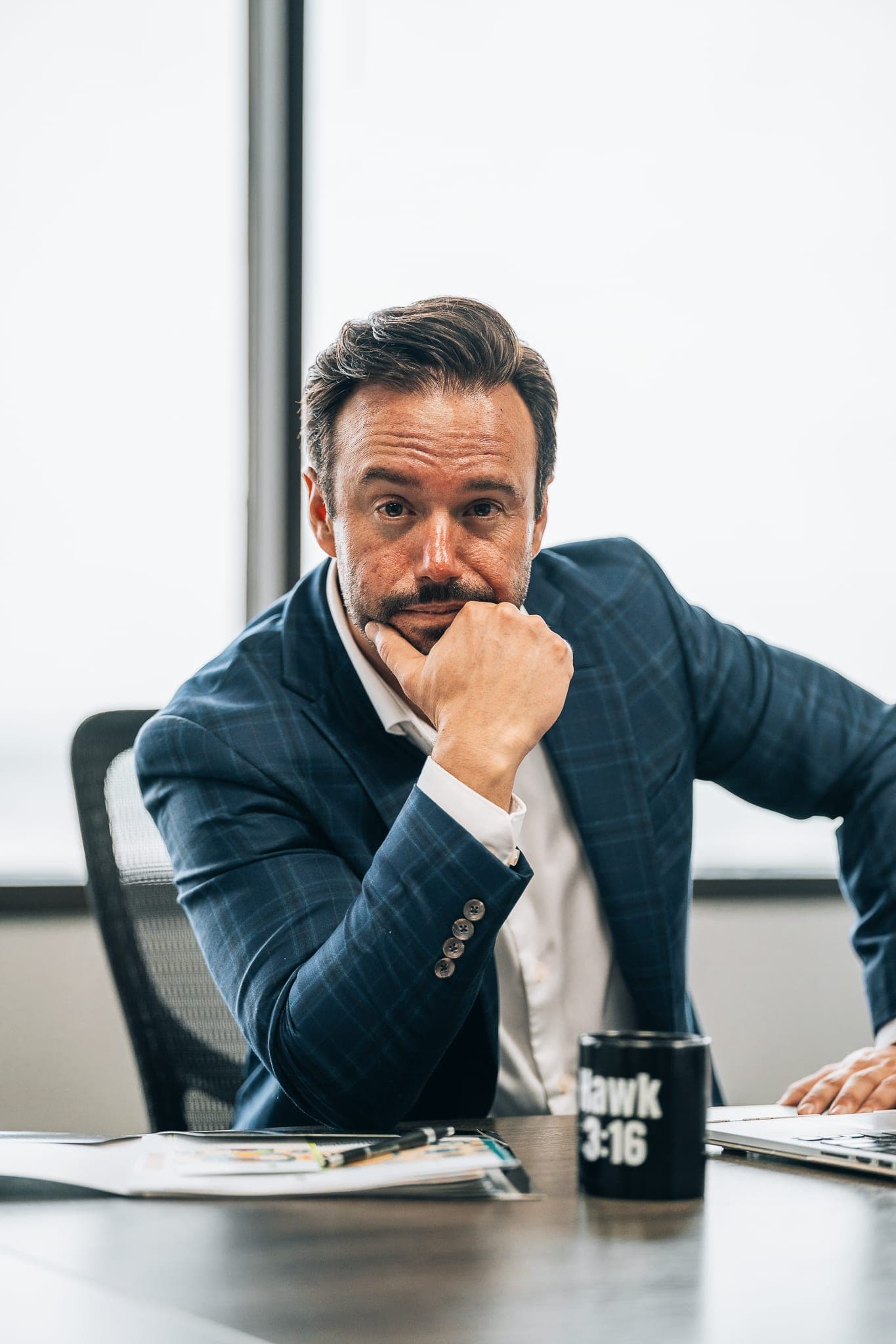 Jonathan Hawkins at his desk, hand on chin, listening thoughtfully