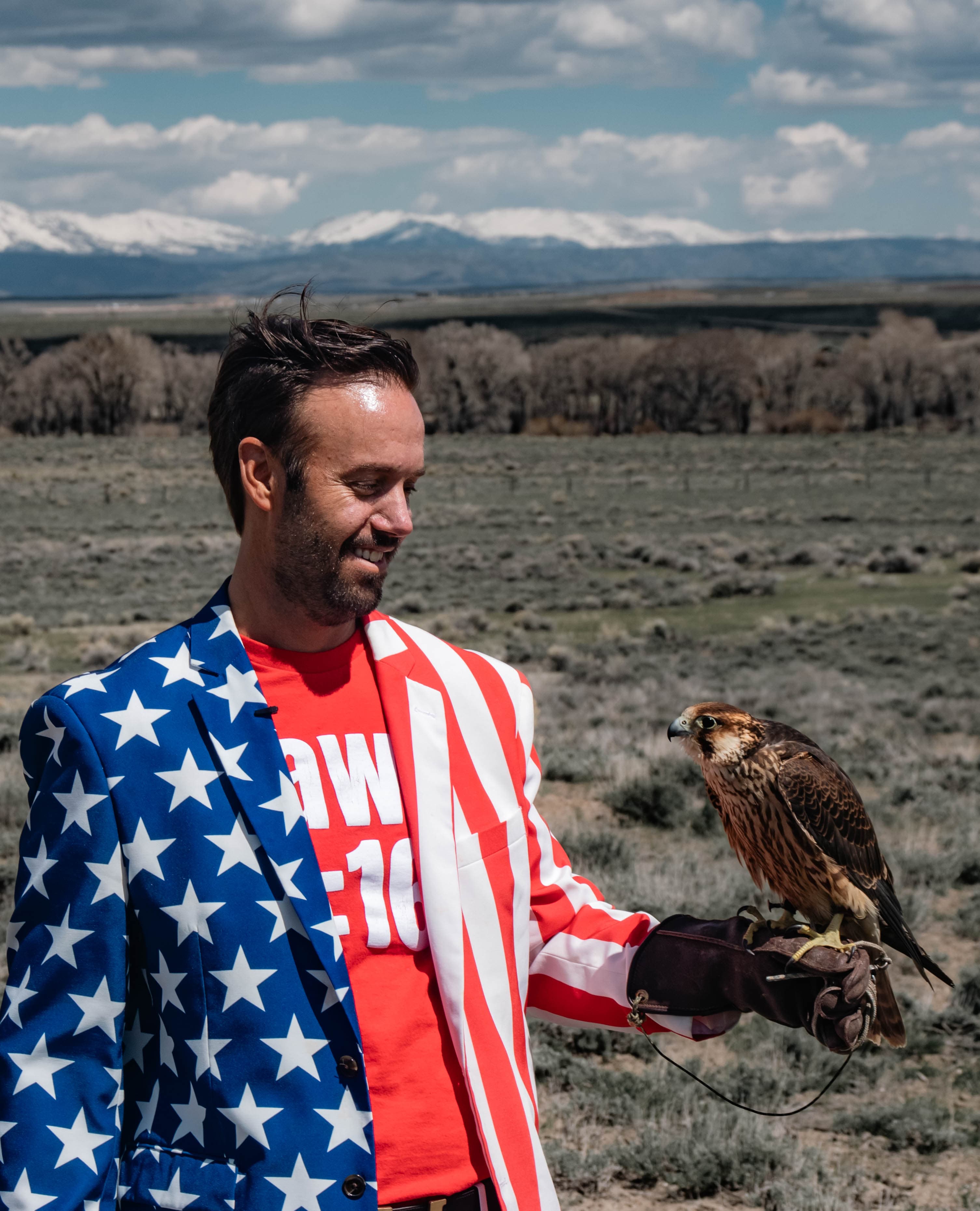 Founder holding hawk in open field